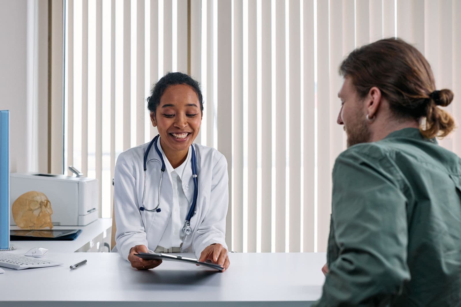 Doctor consulting a patient across a desk in a bright clinic